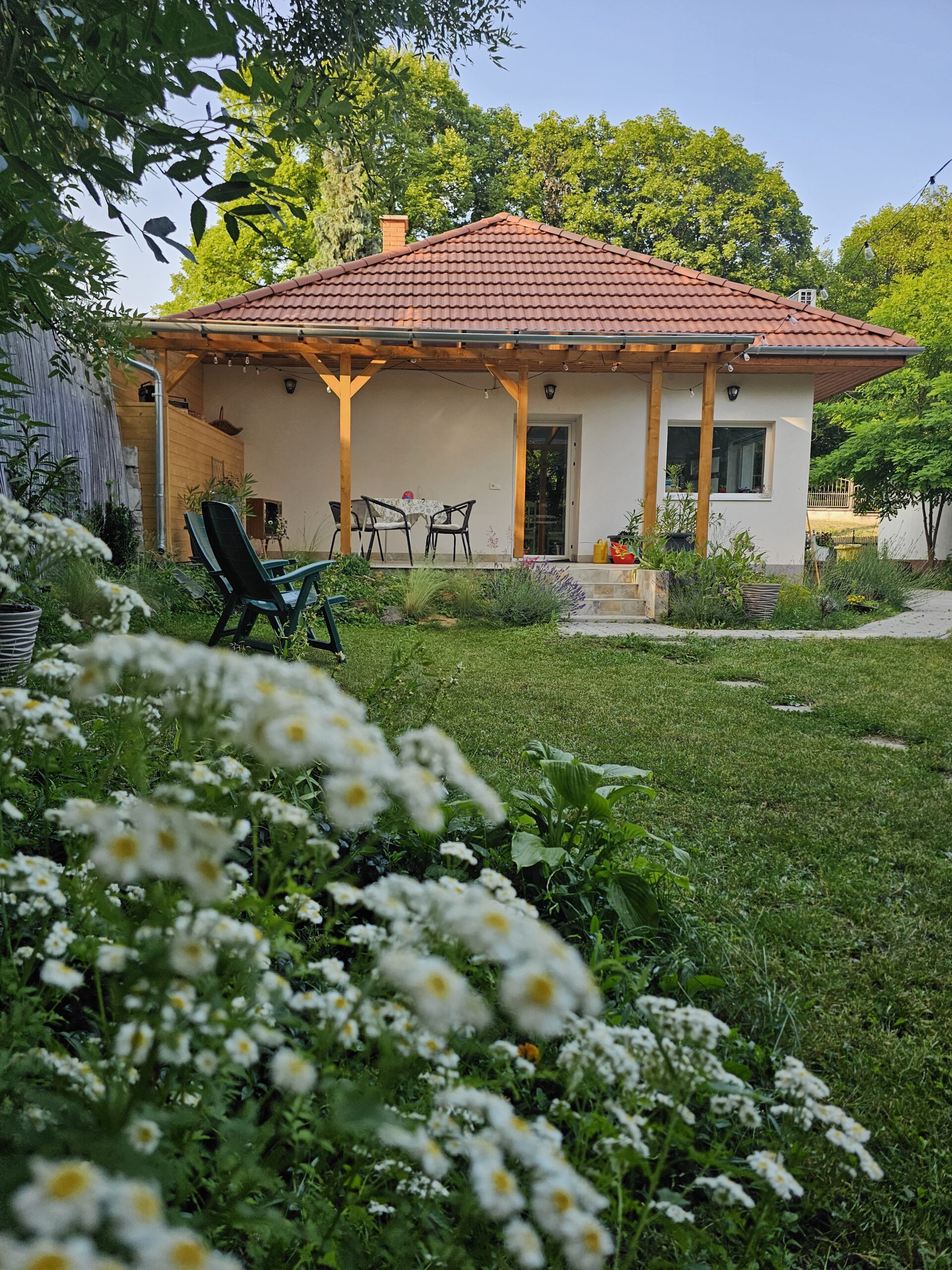 A birslak vendégház épülete a kertből, előtérben virágokkal.